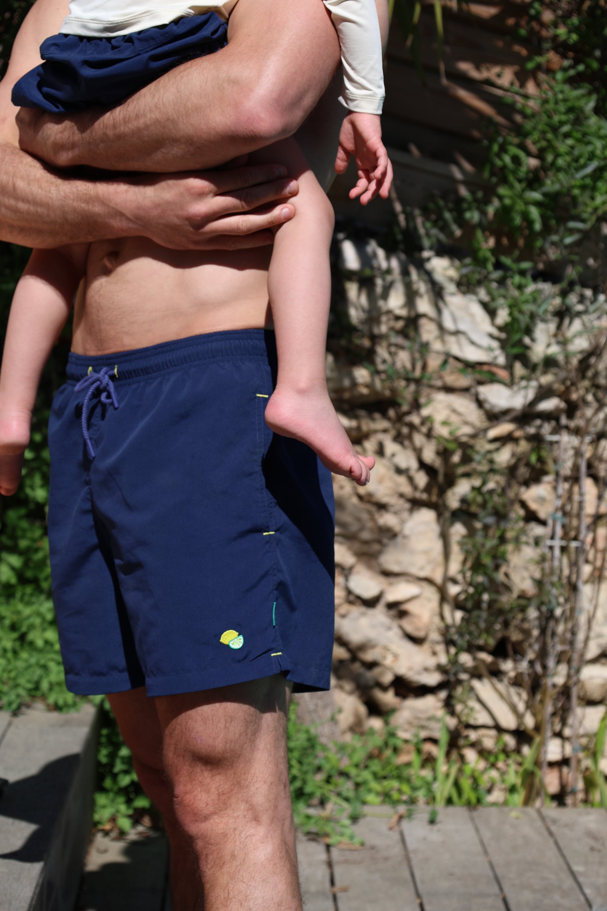 Father and son wearing Loumio Paris Orso Deep Blue swim shorts with citrus embroidery, enjoying summer together