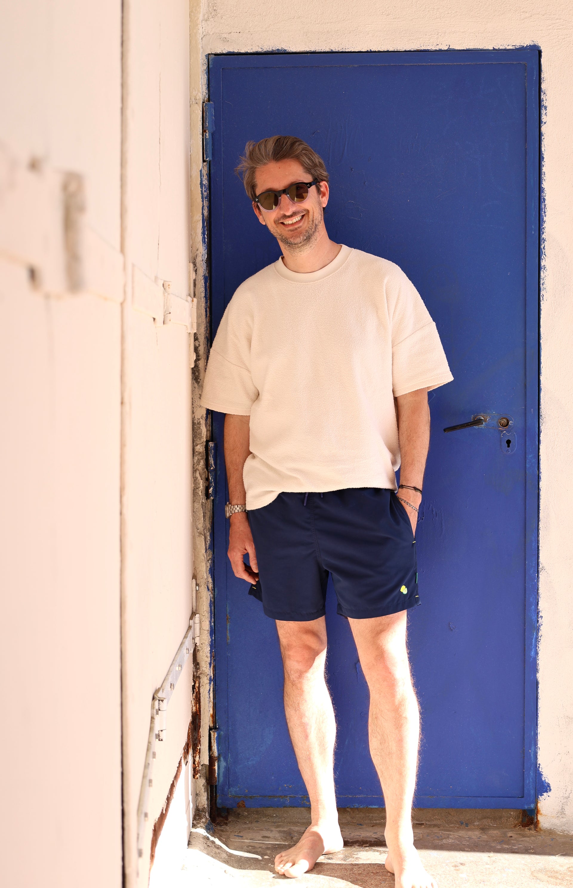 Homme portant le maillot de bain Orso Deep Blue Loumio Paris, prêt pour une journée ensoleillée à la plage