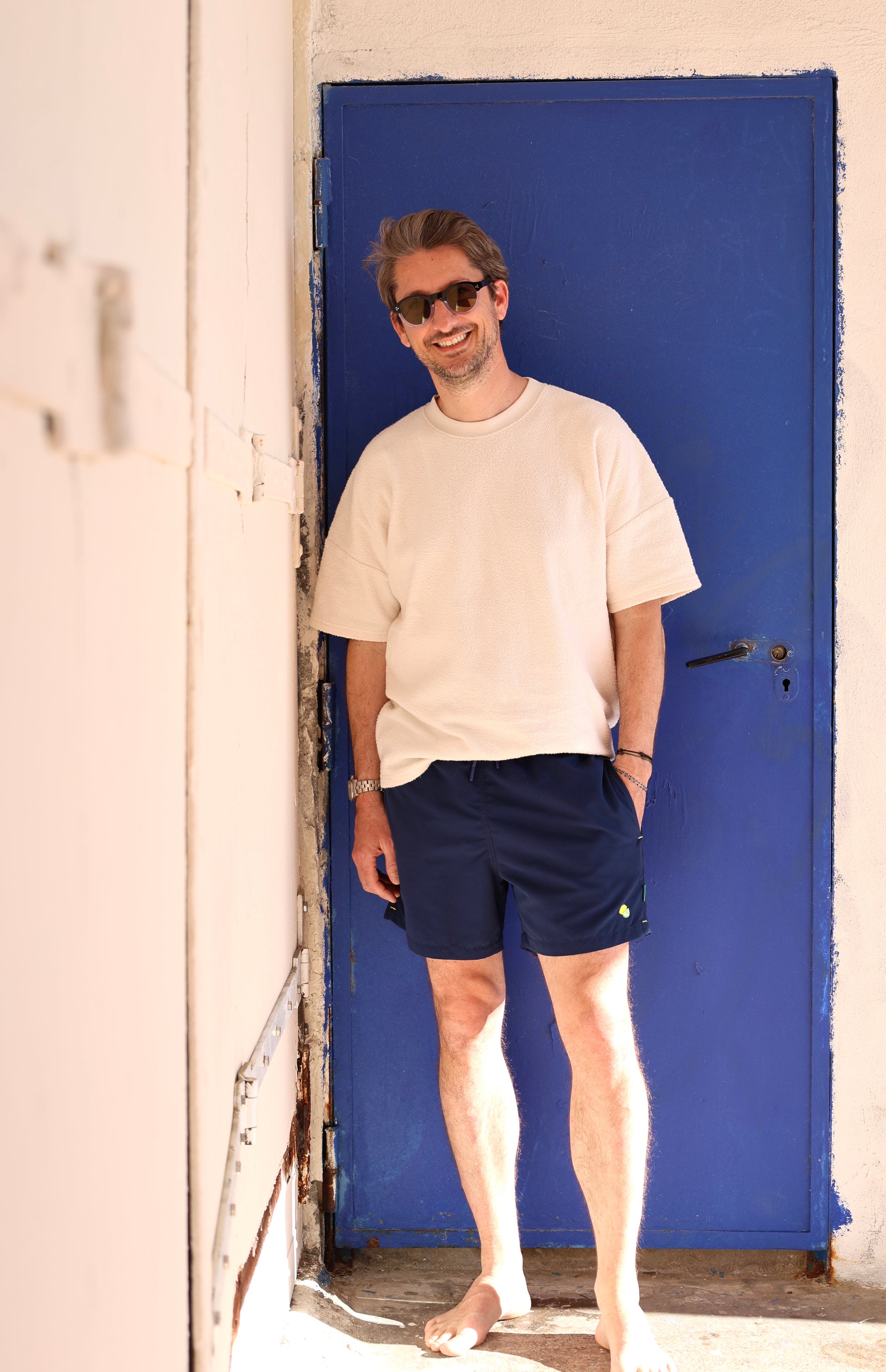 Homme portant le maillot de bain Orso Deep Blue Loumio Paris, prêt pour une journée ensoleillée à la plage