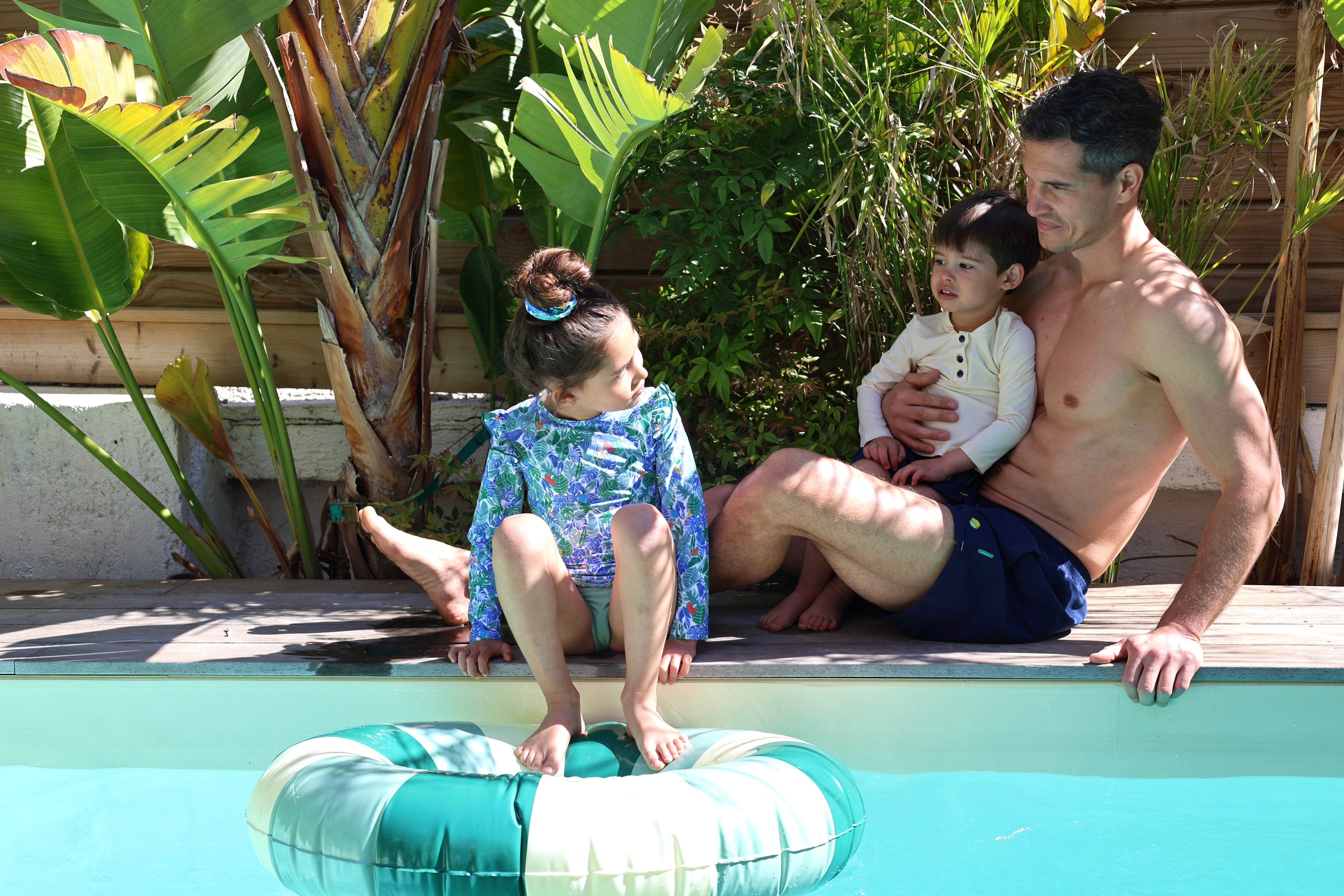Loumio Paris family wearing UV protection outfits: Deep Blue Orso swim shorts and Tropical UV top, ready for summer fun.